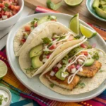 Fresh and colorful fish tacos served with slaw, avocado, and creamy sauce on a vibrant table setting.